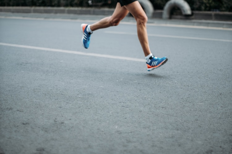 Close-up of a runner's feet mid-stride on pavement