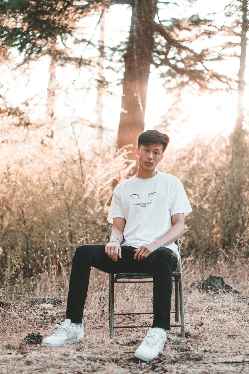 man wearing white crew-neck shirt sitting on gray metal chair