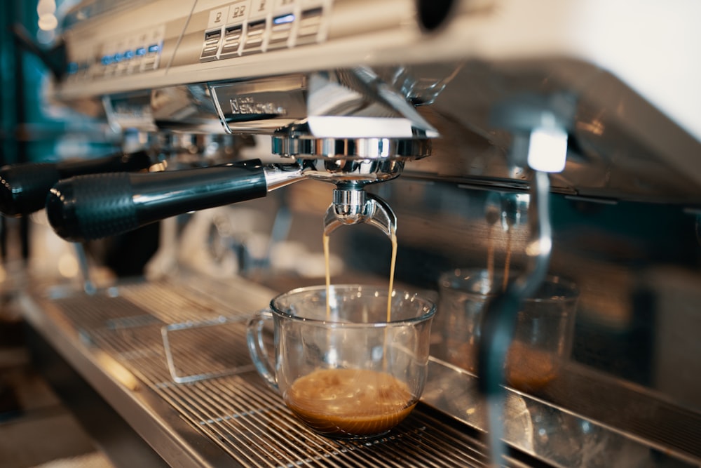 tazza di vetro trasparente che versa caffè da espressore