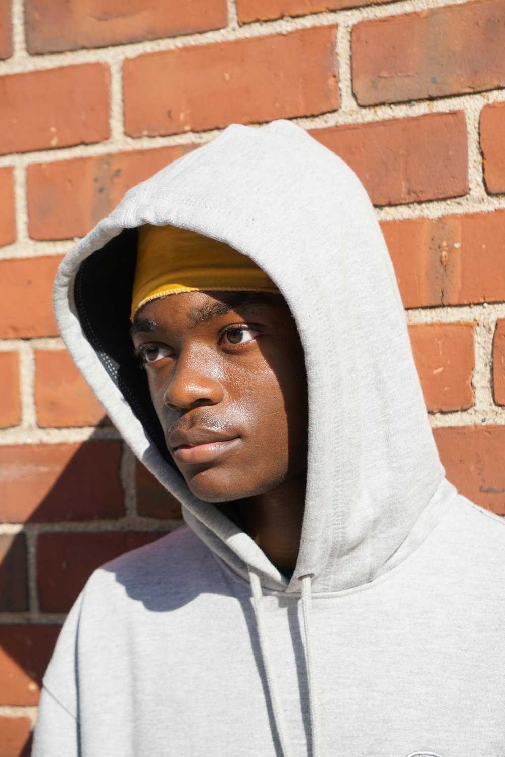 man wearing grey pullover hoodie leaning on wall