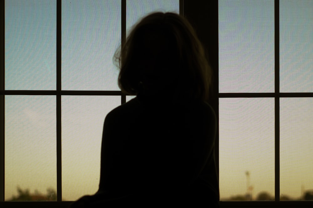 silhouette of woman standing beside window