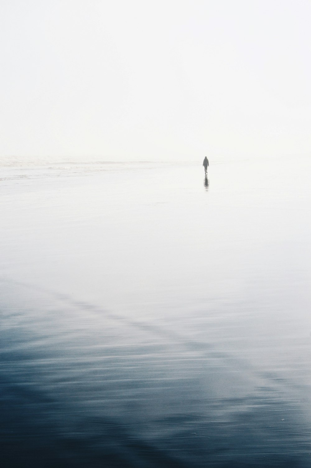 grayscale photo of person standing on seashore