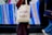 A person is walking while carrying a canvas tote bag with a design promoting diversity, reading 'The Power of Different' along with images of various dogs. The background features a vibrant, abstract display with vertical streaks of color.