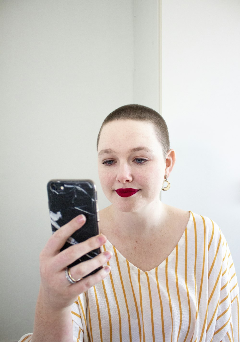 woman in white and yellow striped top holding phone