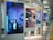 A series of large digital displays are positioned in a subway or transit station setting, each showing different artistic portraits. The nearest display features an image of a woman in a room with blue lighting and decorative items like a mobile and wall art. The scene is modern and artistic, with a focus on individual expressions and creativity.