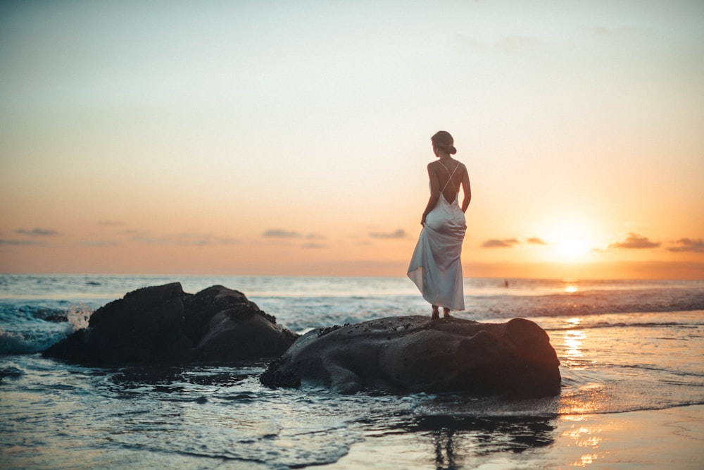 woman standing on rock during golden hour