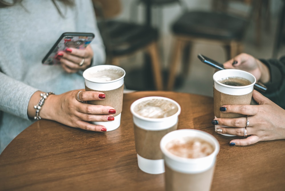 two women holding drinks on wooden surface