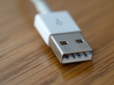 A neatly coiled USB cable and HDMI connector resting on a wooden surface, ready to connect your devices.