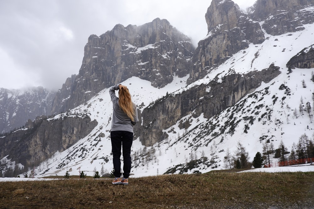 mulher em pé enfrentando montanhas durante o dia