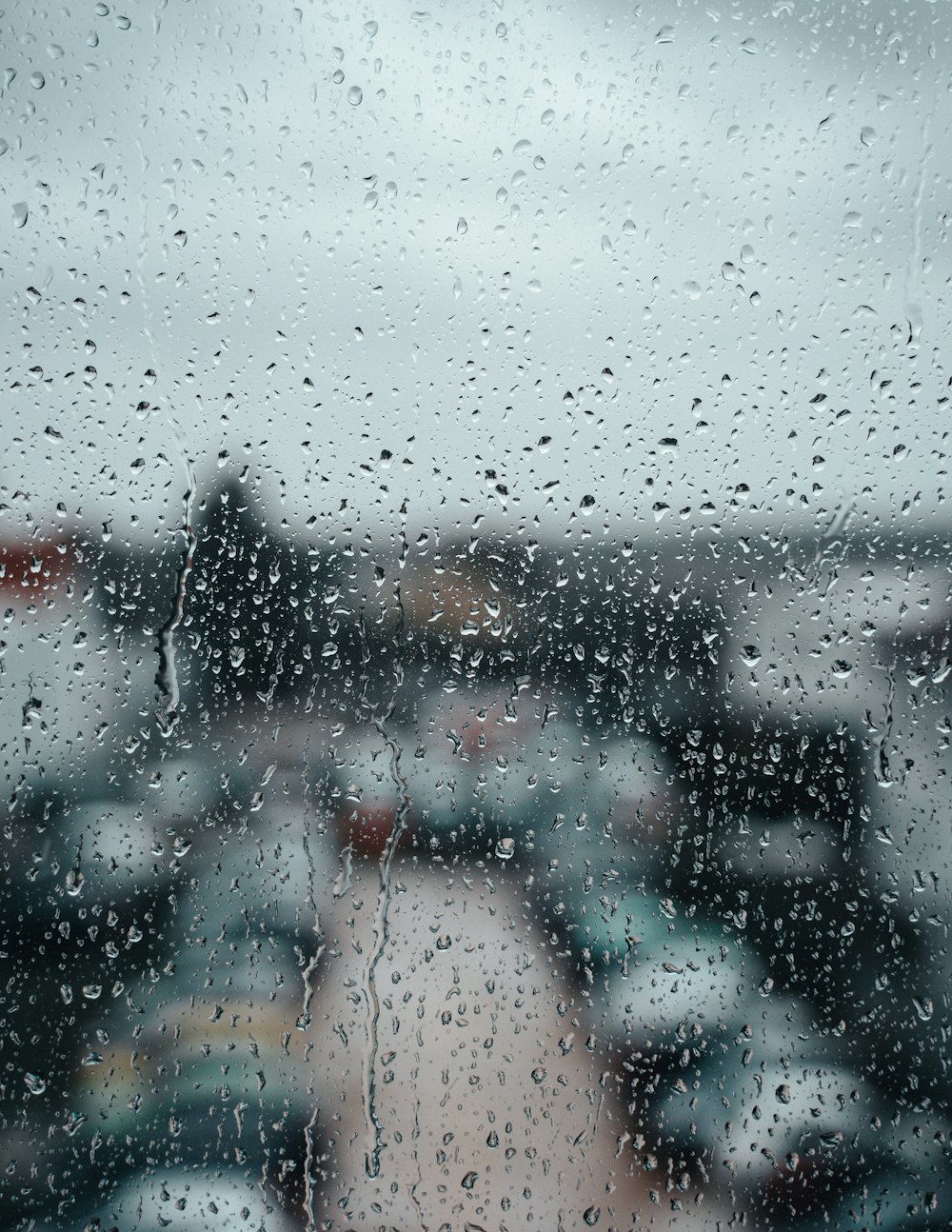 a view of a parking lot through a rain covered window
