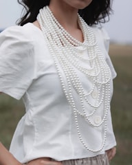 woman wearing white blouse and white pearl necklace