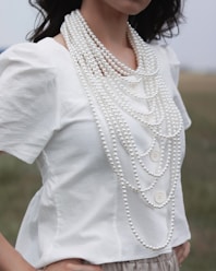 woman wearing white blouse and white pearl necklace