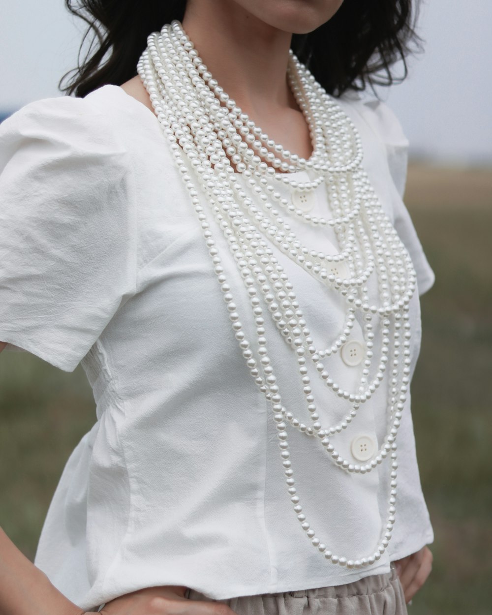 白いブラウスと白い真珠のネックレスを身に着けた女性