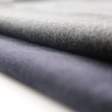 A close-up view of rolled fabric with a soft texture. The fabric appears to have a smooth finish, and the folds suggest it is thick and durable.