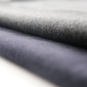 A close-up view of rolled fabric with a soft texture. The fabric appears to have a smooth finish, and the folds suggest it is thick and durable.