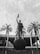 A prominent statue of a figure holding a trophy stands atop a large globe-like base inscribed with 'BRASIL 1958 1962'. The statue is surrounded by tall palm trees, and in the background, there's a large circular building with columns.