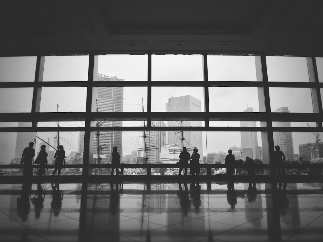 grayscale photography of people standing inside building near window