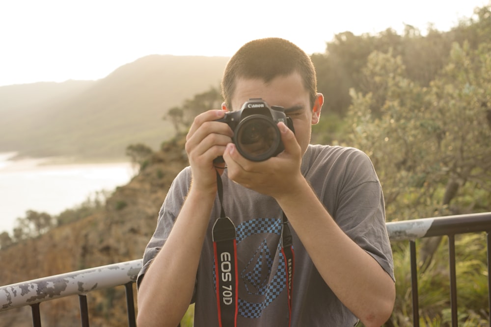 man wearing gray and blue crew-neck t-shirt standing while taking photo