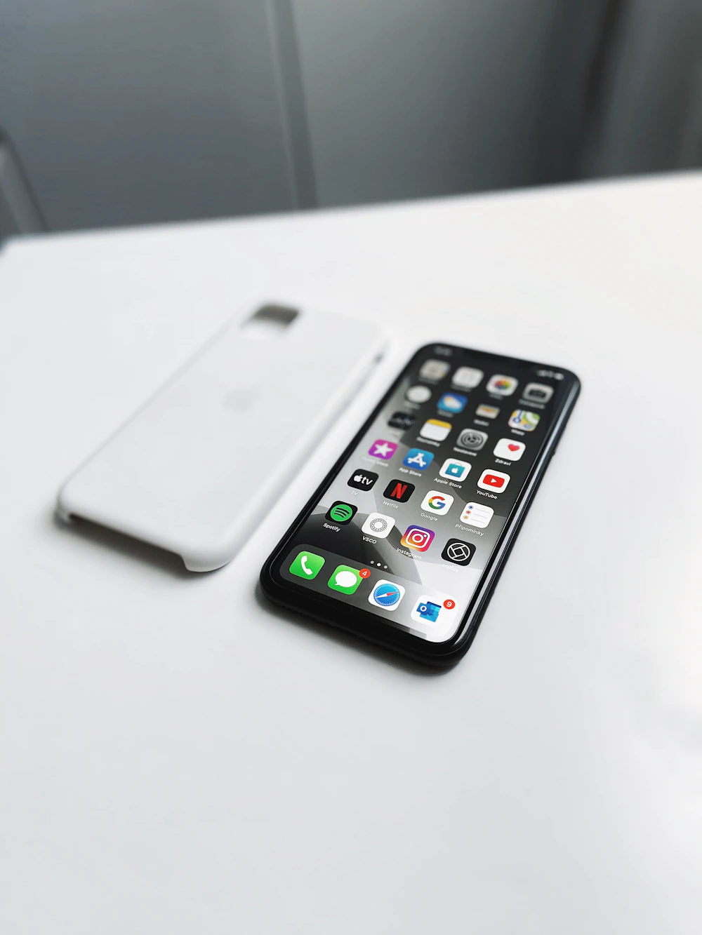 Zilveren iPhone naast een wit hoesje op een witte ondergrond