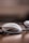 A close-up view of a pair of eyeglasses, positioned on a smooth, reflective surface. The lenses and frames are in focus while the background is blurred, creating a depth of field effect.