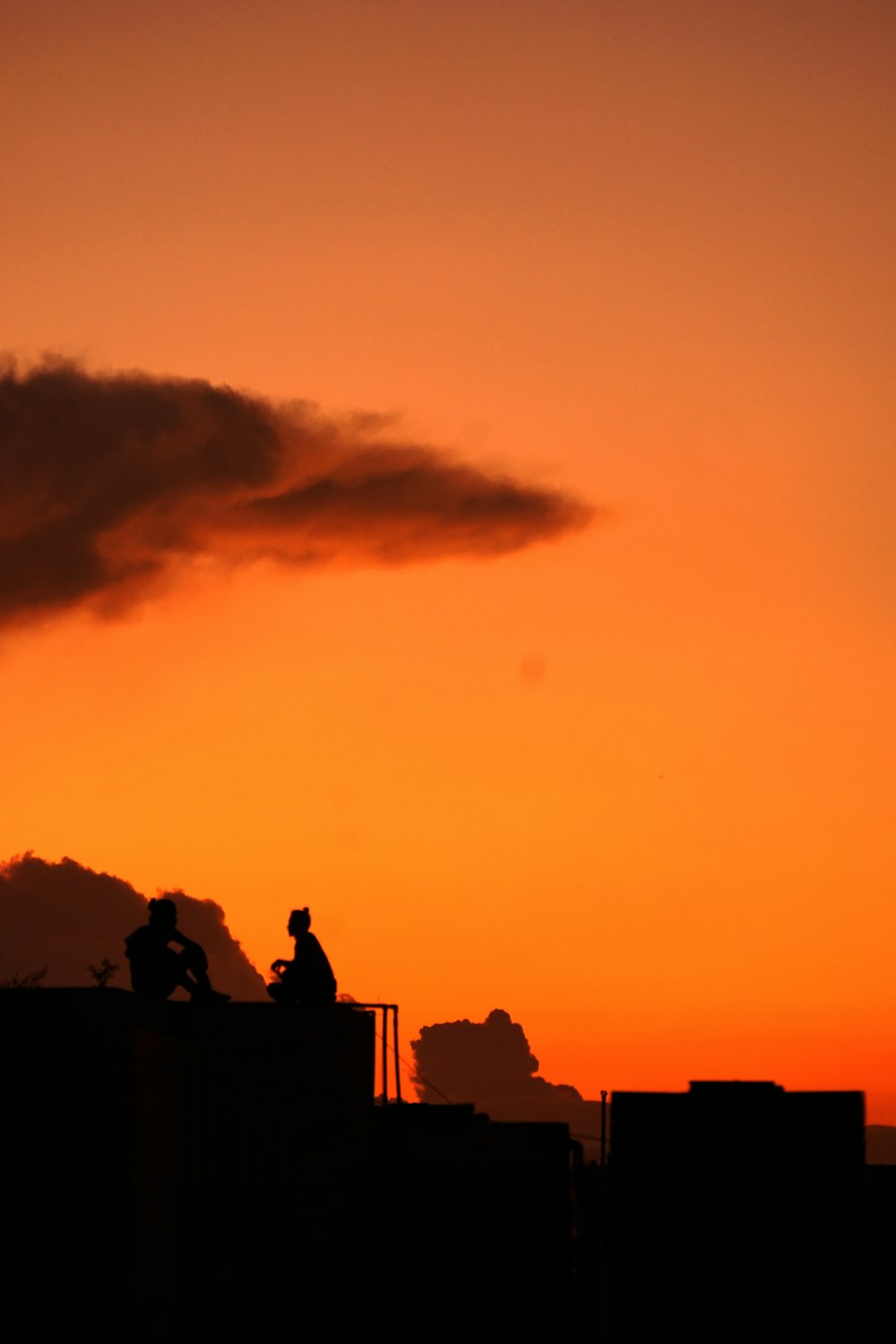 silhouette di persone sedute sugli edifici durante l'ora d'oro