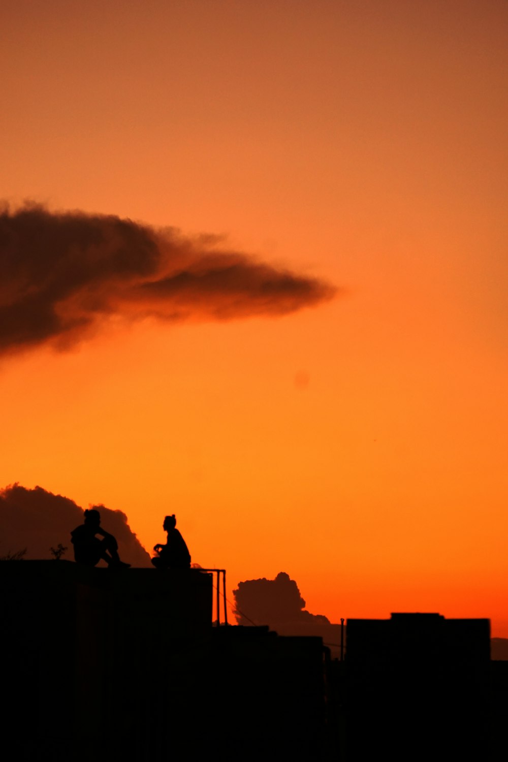 silhouette of people sitting on buildings during golden hour