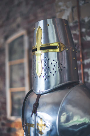 Close-up of a striking Viking helmet adorned with Egyptian scarab motifs, set against a textured stone background.
