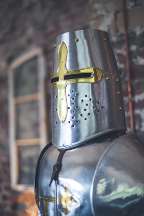Close-up of a warrior’s helmet resting on a stone wall at dusk.