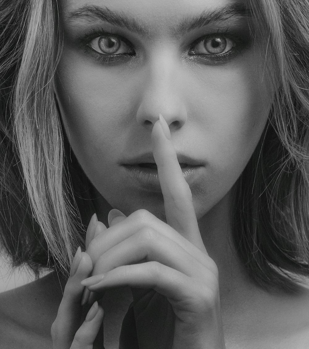 grayscale photography of woman doing silent sign