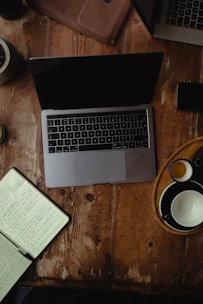 A cozy workspace with a laptop, notebook, and coffee cup, hinting at creative writing in progress.