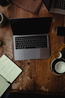 A cozy workspace with a laptop, coffee cup, and shopping packages on a wooden table.