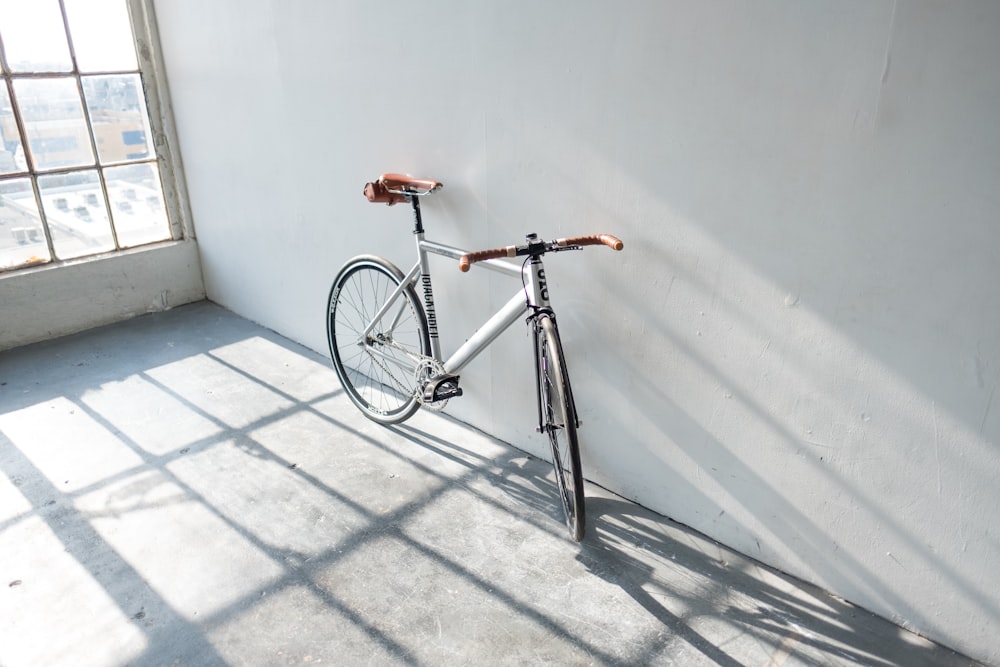 white road bike leaning on wall