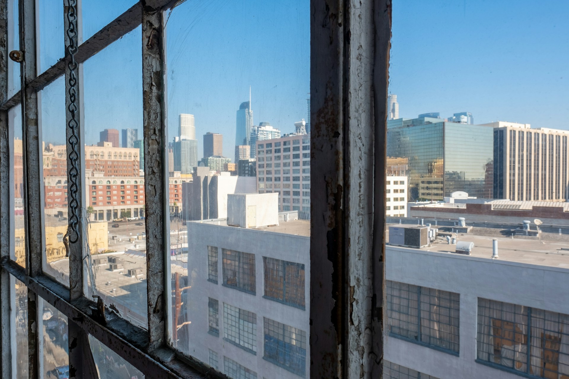 Close-up of a skylight being carefully inspected and cleaned, with the city skyline visible through the shining glass above.