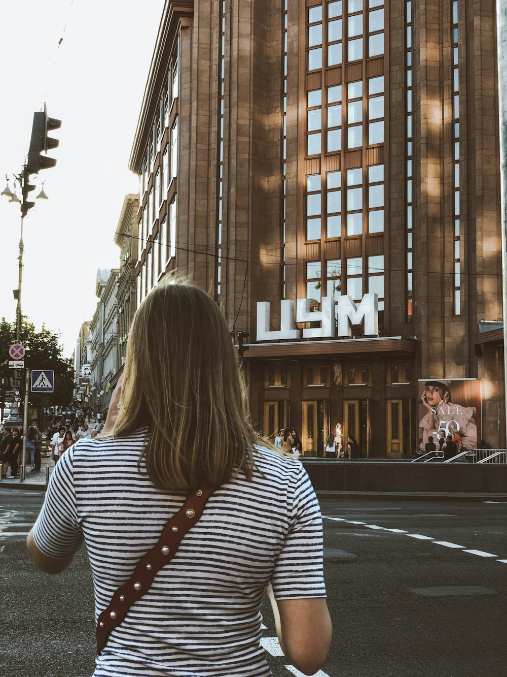 woman wearing black and white stripe shirt across LLYM building