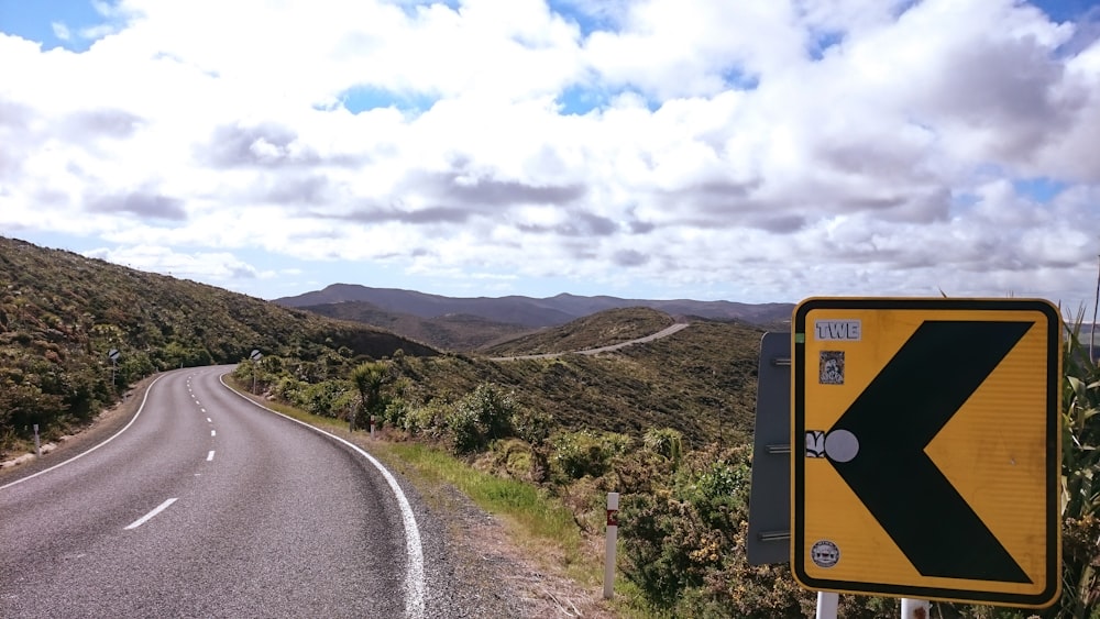 Señal de flecha izquierda negra y amarilla cerca de la carretera