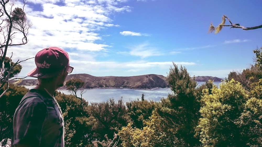 a man wearing a red hat looking out over a lake