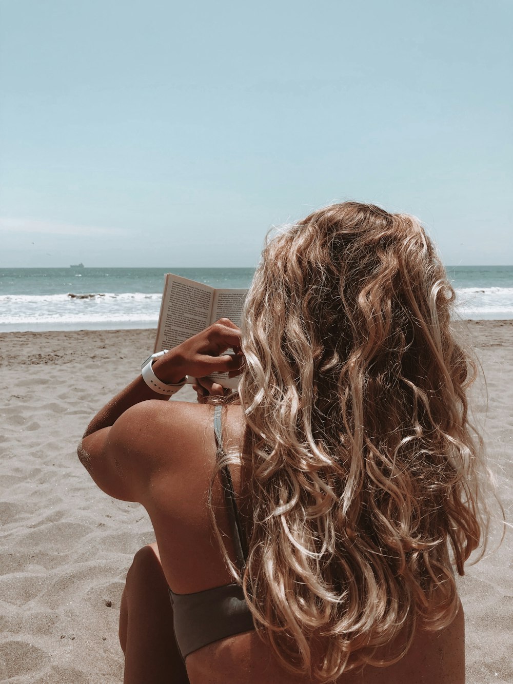 woman in brown bikini holding book