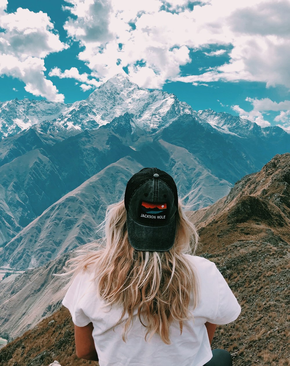 woman in white top sitting on hill