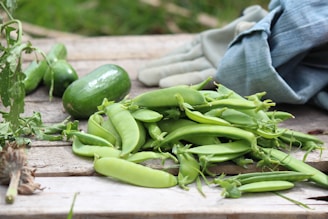 Set of colorful gardening gloves placed next to freshly harvested vegetables.