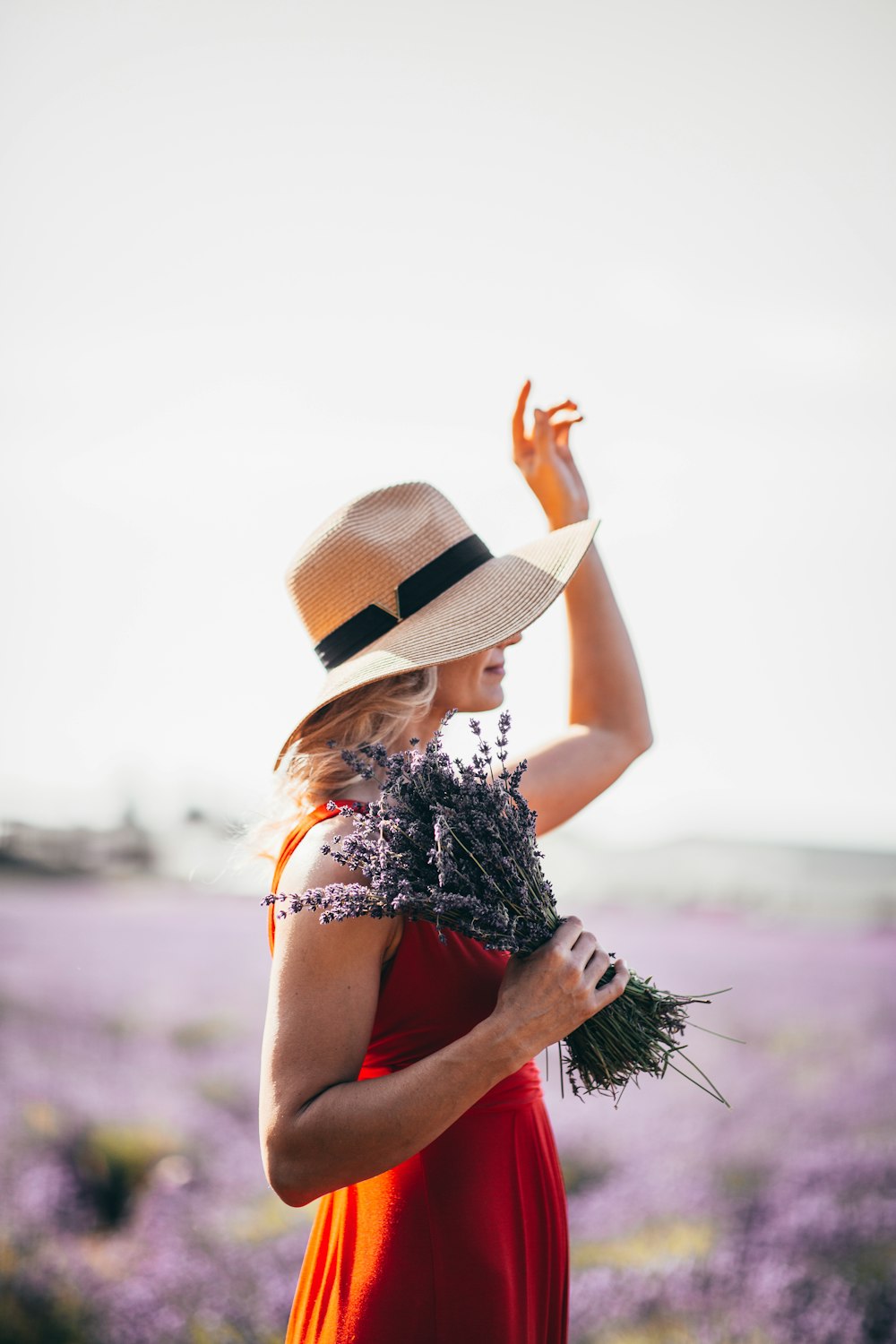 mujer con vestido rojo sin mangas sosteniendo flores de lavanda