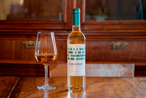 white and blue labeled bottle beside wine glass