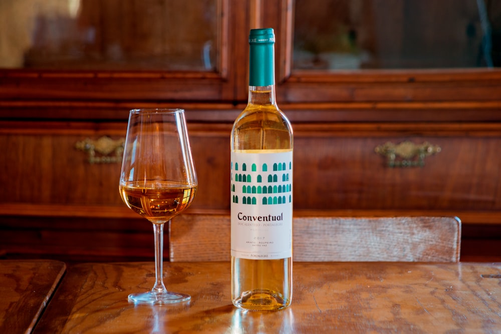 white and blue labeled bottle beside wine glass