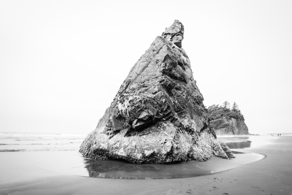 grayscale photography of rock formation beside body of water