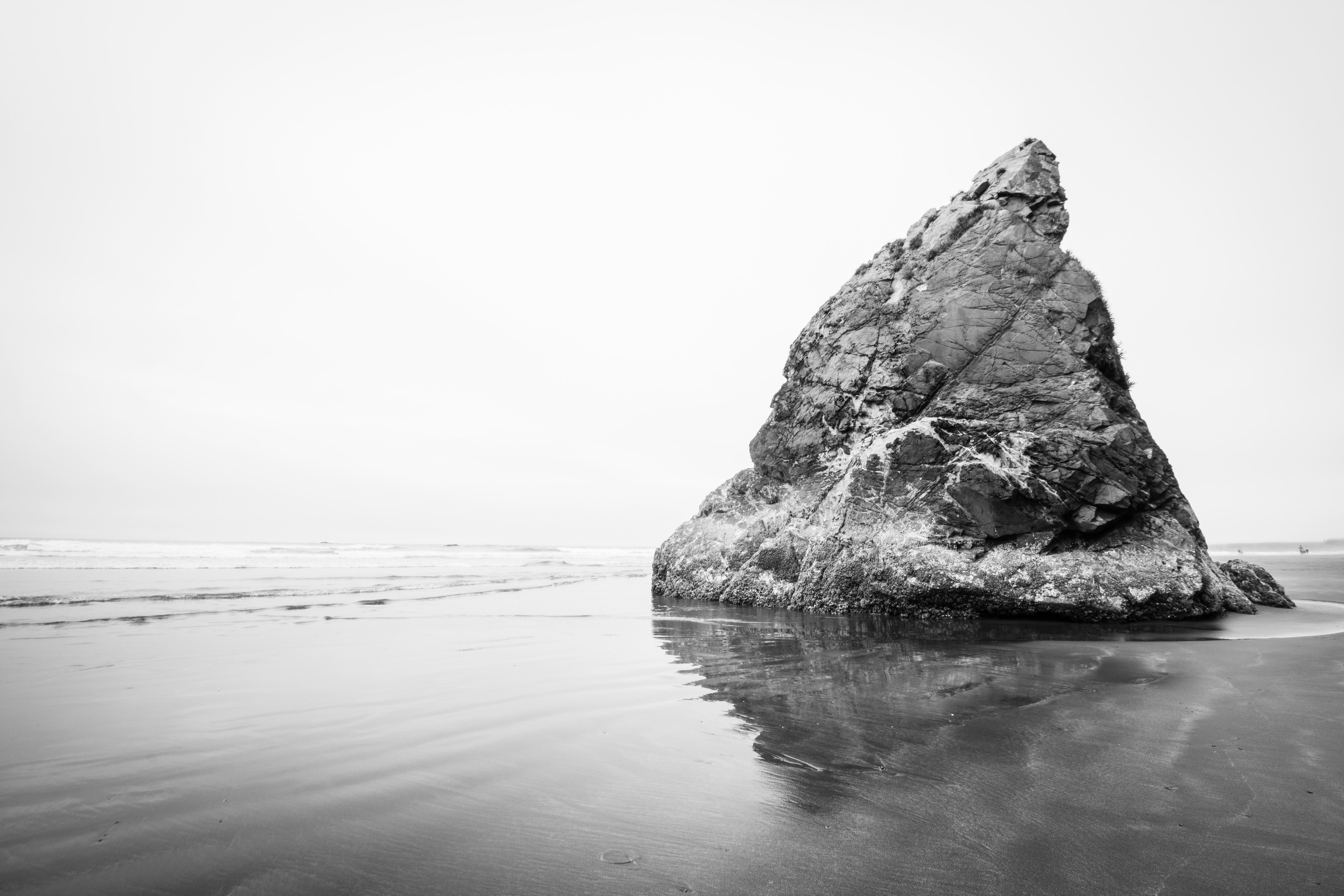 grayscale photography of rock formation beside body of water