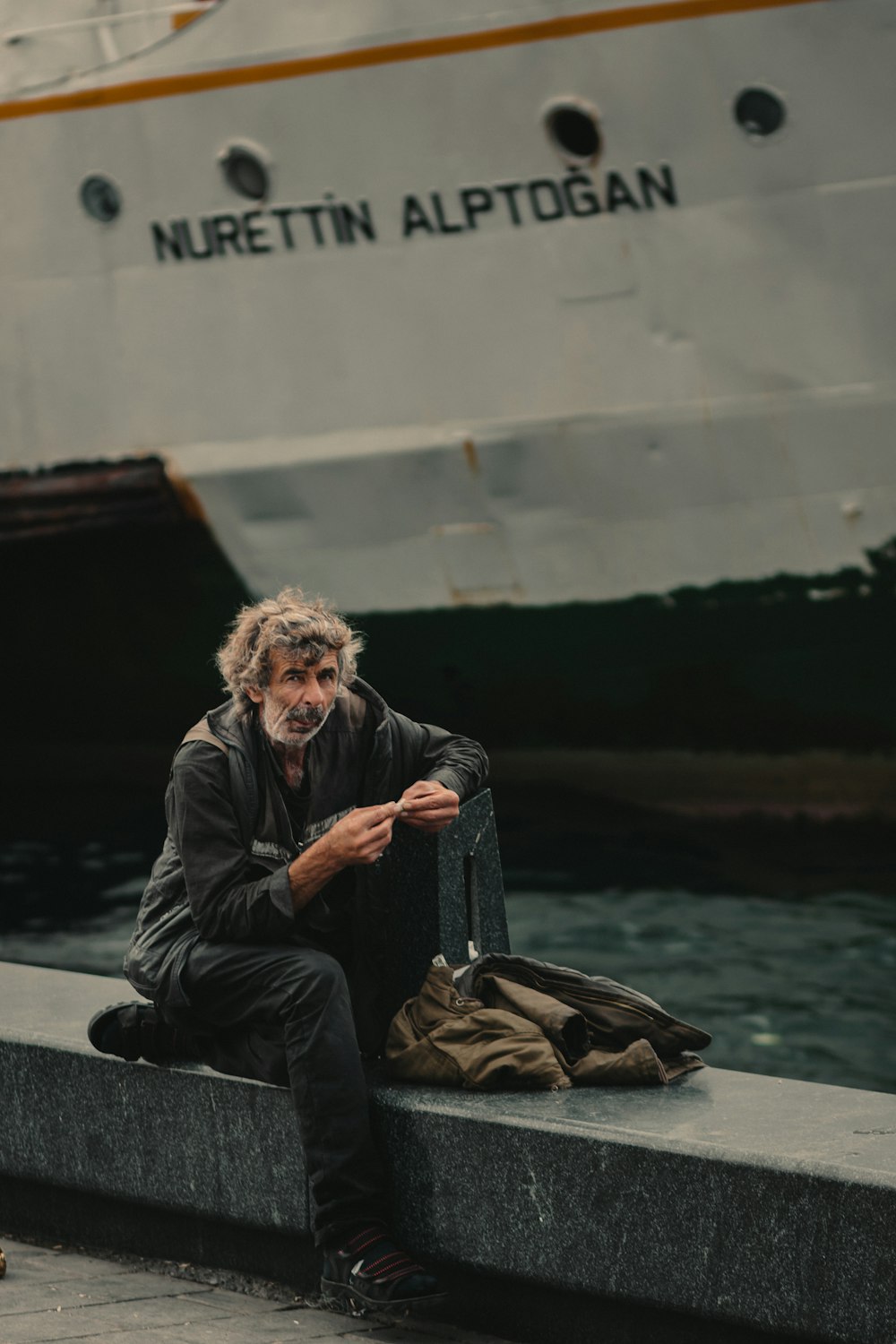 Mann sitzt in der Nähe eines Segelschiffs