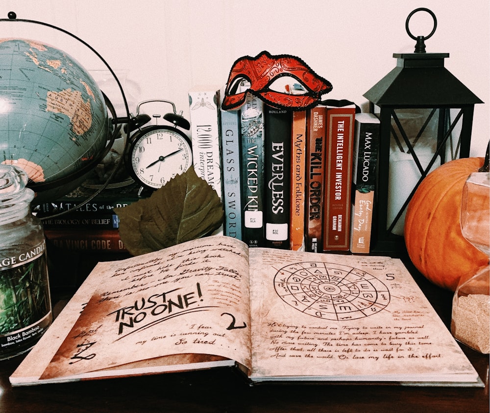 book page surrounded with books, lantern, and desk globe
