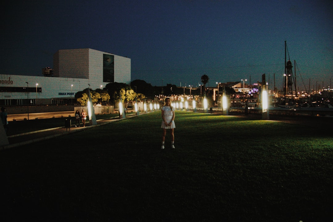woman standing on grass field near buildings during night