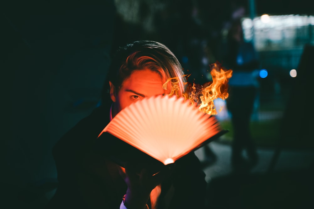 Photographie sélective de mise au point d’un homme ouvrant un livre avec une flamme