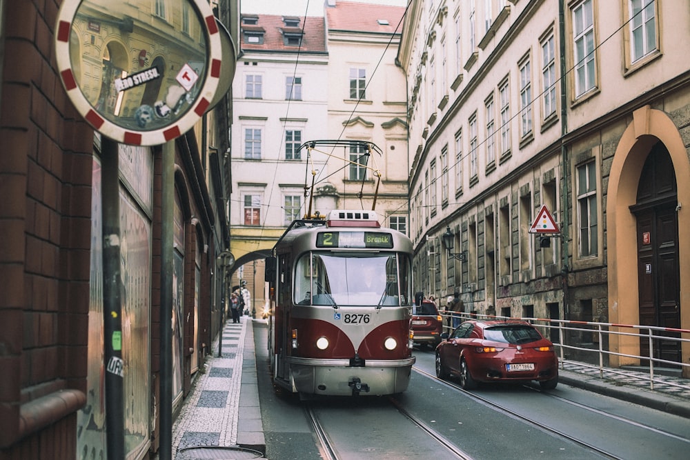 red tram and car passing by city street