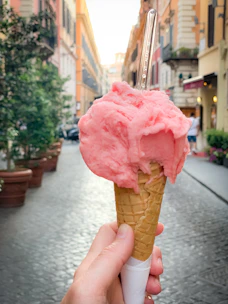 A scoop of creamy gelato in a waffle cone with Radium Hot Springs scenery behind.